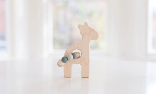 Wooden toy giraffe on a white surface with a blurred background